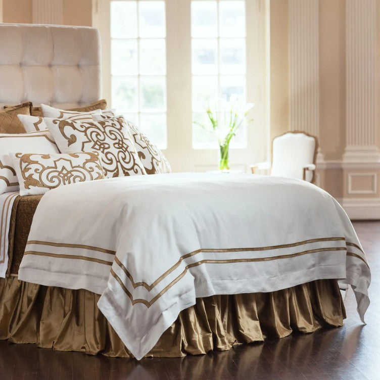 Neatly made bed with white and gold bedding in a bright bedroom. Lili Allesandra bedding and pillows
